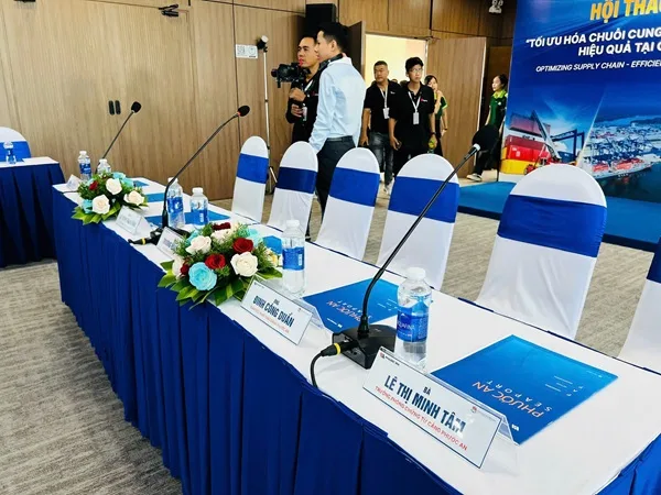 Bàn đại biểu được chuẩn bị micro, tài liệu và hoa trang trí tại Hội thảo Cảng Phước An.