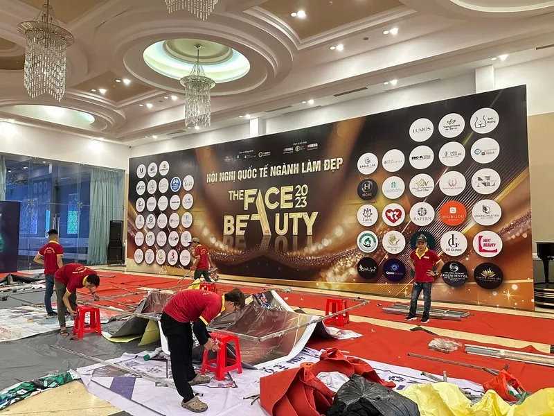 Đội ngũ kỹ thuật thi công backdrop và hoàn thiện khu vực sân khấu cho hội nghị ngành làm đẹp.