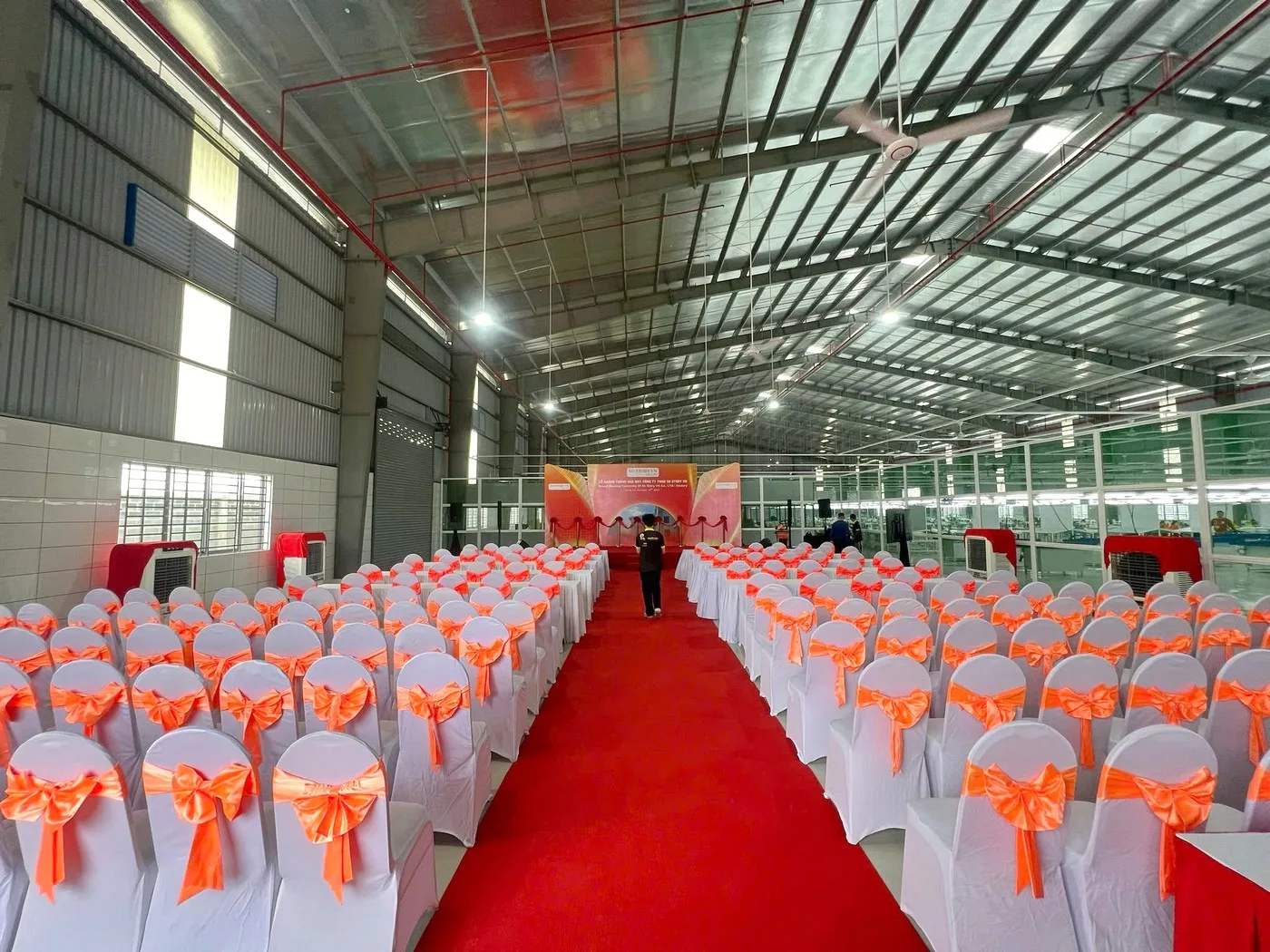 Khu vực khách mời được bố trí ngay ngắn với lối thảm đỏ hướng về sân khấu Bàn ghế khách mời được bố trí theo hàng tại lễ khánh thành nhà máy